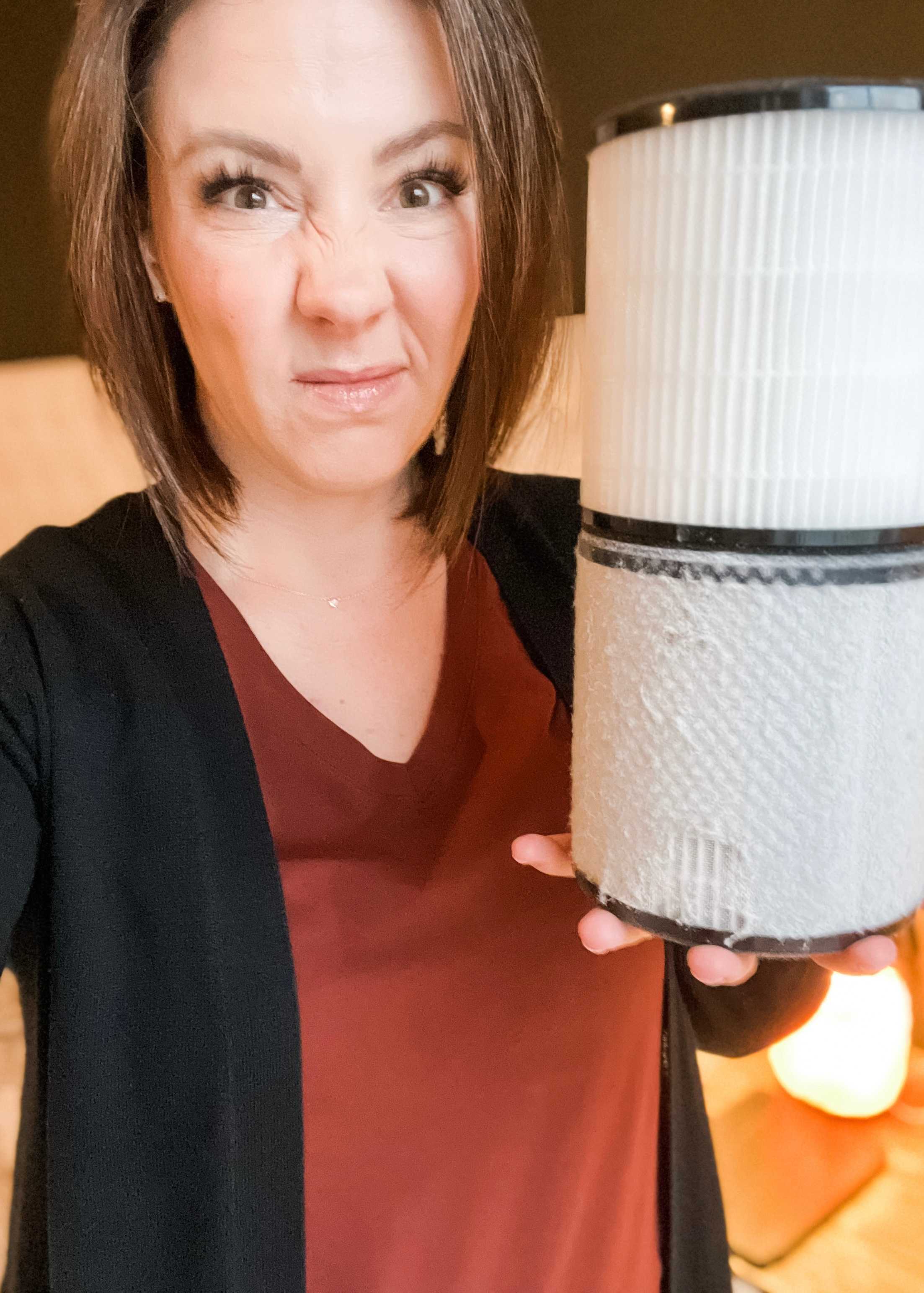 Picture of Kathryn holding a clean Scentsy air purifier filter next to a dirty one